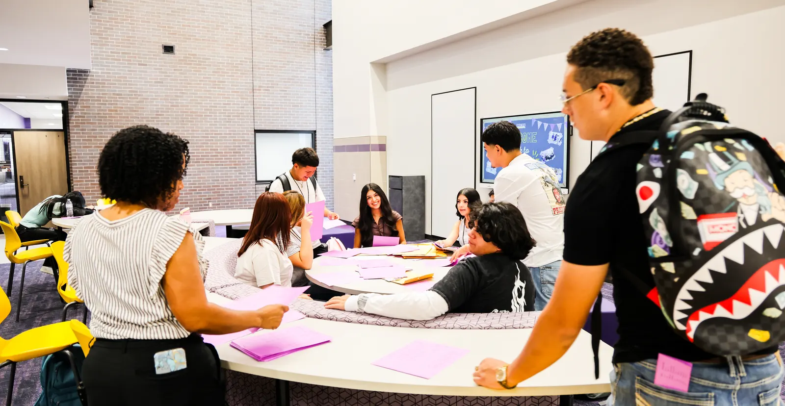 A Pecos-Barstow-Toyah ISD teacher working with a group of high school students around a round table in a classroom